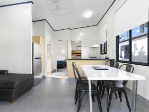 Ingenia Holidays Noosa North في تيوانتين: مطبخ وغرفة طعام مع طاولة وكراسي بيضاء