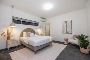 1 dormitorio con 1 cama grande y 1 silla en KORO7 - Boutique Bliss, en Henley Brook