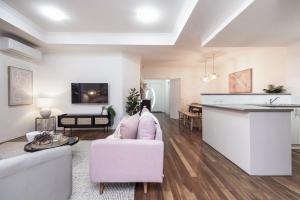 sala de estar con sofá rosa y cocina en KORO7 - Boutique Bliss, en Henley Brook
