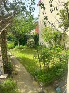 um jardim com relva verde e árvores ao lado de um edifício em Chambre au calme em Colombes