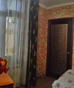 ein Schlafzimmer mit einer Tür, Vorhängen und einem Bett in der Unterkunft 锦江LoveMyHome in Almaty