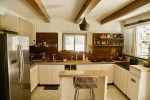 a kitchen with white cabinets and a stainless steel refrigerator at Beach-Front Sumbawa Surf House in Lemonga