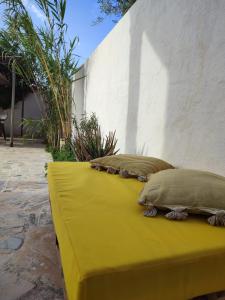 two pillows sitting on a yellow couch next to a wall at Maison d'artiste en Chambre Privée in Temlale