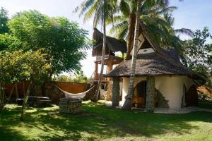 Casa con techo de paja y hamaca al aire libre en Beach-Front Sumbawa Surf House en Lemonga