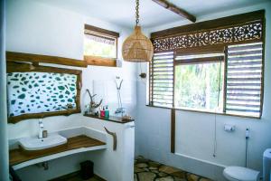 a bathroom with a sink and a toilet and a window at Beach-Front Sumbawa Surf House in Lemonga +58 photos