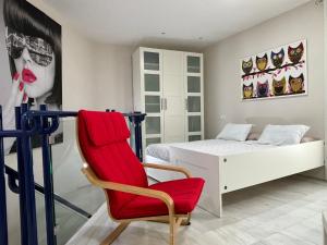 Un dormitorio con una silla roja y una cama en Casa Yaye Aguabajo, en Écija