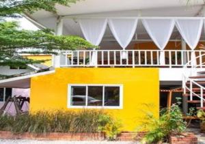 a yellow house with a white balcony at PRAKAI RESORT in Ban Don Klang