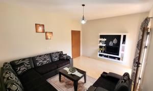 a living room with a black couch and a tv at Vila Dean in Berat