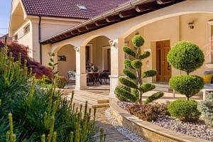a house with a courtyard with trees and bushes at Sika Royal Garden & Spa Central Apartment Arad in Arad