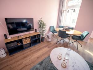 salon z telewizorem, stołem i krzesłami w obiekcie Ferienwohnung "Fünf Freunde" w mieście Erfurt