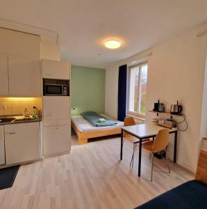 a room with a kitchen and a small room with a bed at Casa Maria Apartments in Solothurn