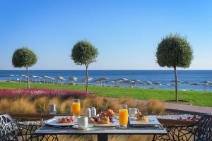 einen Tisch mit Speisen, Orangensaft und dem Meer in der Unterkunft Elysium Resort & Spa in Faliraki