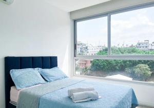 a bedroom with a blue bed with a large window at Airbnb Guayaquil, Puerto Santa Ana, Parking Gratis in Guayaquil +72 photos