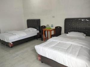 1 dormitorio con 2 camas y mesa con sillas en Kempu Tigan, en Berastagi
