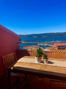 una mesa de madera con 2 macetas en el balcón en Casa Ferro Portosín, en Portosín