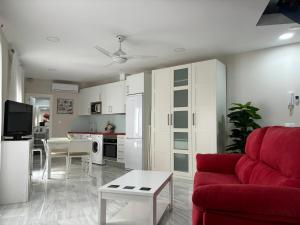 sala de estar con sofá rojo y cocina en Casa Yaye Aguabajo, en Écija