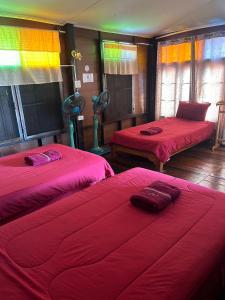 um quarto com duas camas com lençóis vermelhos e um arco-íris em Baan Are Gong Riverside Homestay em Phra Nakhon Si Ayutthaya