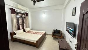 a bedroom with a bed and a flat screen tv at Astachal Homestay in Guwahati
