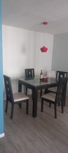 uma mesa de jantar com cadeiras e uma garrafa de vinho em Movistar Apart Santiago em Santiago
