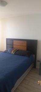 uma cama com uma cabeceira em madeira num quarto em Movistar Apart Santiago em Santiago