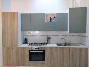 La cuisine est équipée de placards blancs et d'un four avec plaques de cuisson. dans l'établissement Emy Wine house, à Porto Recanati