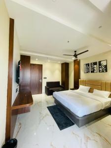 een slaapkamer met een groot wit bed en een bank bij Hotel Narmada Residency in Sambalpur