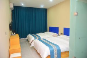 哈尔滨Hongge Hotel - Harbin Taiping Airport的配有蓝色窗帘的客房内的两张床