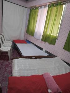 a bedroom with two beds and a chair and a window at QUICKSHIELD HOMESTAY in Naga