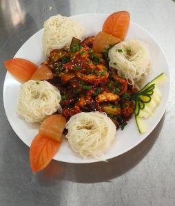 un plato de comida con espaguetis y fideos en una mesa en 소문난게스트하우스, en Kanchipuram