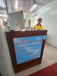 a man standing behind a counter with a sign at 소문난게스트하우스 in Kanchipuram