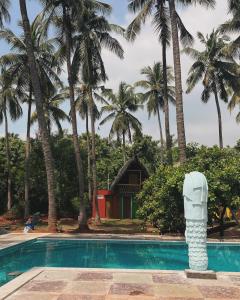 a swimming pool with palm trees and a house at Nature Zone Resort in Puducherry