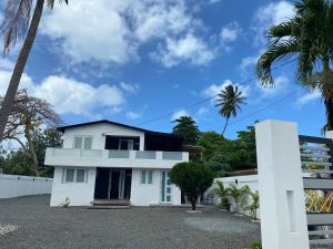 a white house with palm trees in front of it at Modern Beach Retreat: 1-Bed Apt at Villa Iris in Luquillo