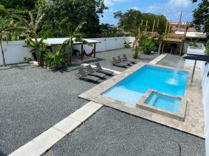 a backyard with a swimming pool and chairs and a house at Modern Beach Retreat: 1-Bed Apt at Villa Iris in Luquillo