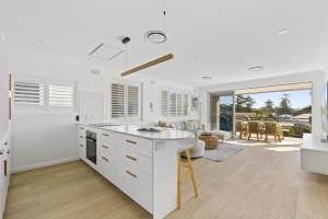 uma cozinha com bancadas brancas e uma sala de estar em Stunning 2-Bed Coastal Pad Across From the Beach em Sydney