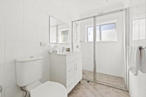 uma casa de banho branca com um WC e um chuveiro em Stunning 2-Bed Coastal Pad Across From the Beach em Sydney