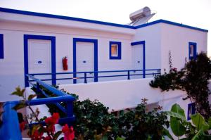 a white building with blue doors and some flowers at Hotel Tigaki's Star in Tigaki