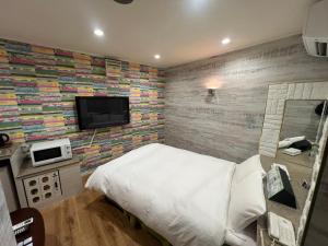 um quarto com uma cama e uma televisão na parede em Hotel Firstwood 大栄店 em Narita