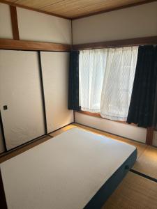 Habitación pequeña con colchón frente a una ventana en 高知県　みどりの家 en Gomen