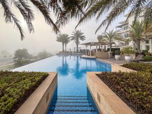 einen Pool mit blauem Wasser und Palmen in der Unterkunft Frank Porter - Ansam Building 1 - Yas Island in Abu Dhabi