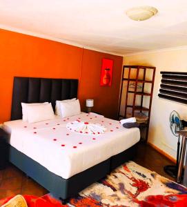 Avela Lodge في Hekpoort: غرفة نوم بها سرير كبير وعليها زهور حمراء