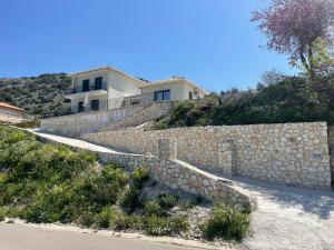 una casa en una colina con una pared de piedra en Anemar Lefkada, en Drymon