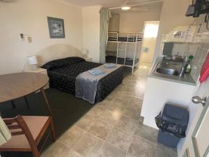 1 dormitorio con 1 cama, lavamanos y mesa en Warrego Motel, en Charleville