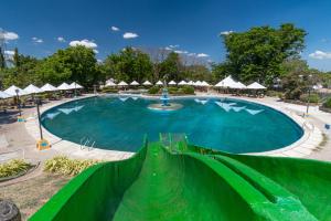 a large swimming pool with a green fence around it at One Alo Hotel and Resort in Manaoag