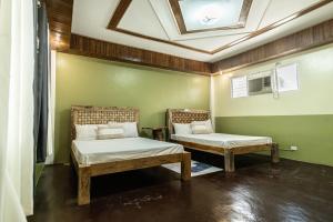 Habitación con 2 camas y techo. en One Alo Hotel and Resort, en Manaoag
