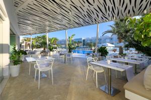 restauracja ze stołami i krzesłami oraz basenem w obiekcie Blanco Hotel Formentera w mieście Es Pujols