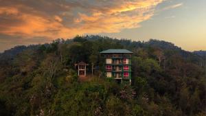 Hilton Cloud Resort في واياناد: مبنى على قمة تل به اشجار