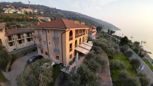 une maison sur une colline à côté de l'eau dans l'établissement Hotel Garden, à Torri del Benaco