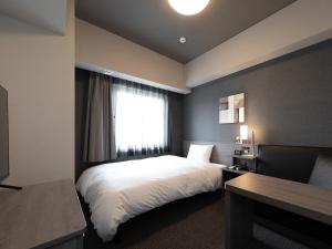 una camera con un letto bianco e una finestra di Hotel Route Inn Kyoto Kameoka a Kameoka