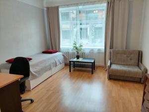 a bedroom with a bed and a chair and a window at Bright spacious apartment with street parking in Rīga