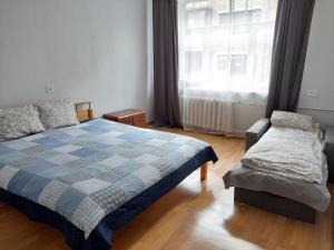 a bedroom with a bed and a chair and a window at Bright spacious apartment with street parking in Rīga